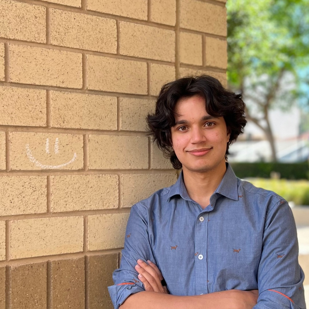 Ruslan Manoharan standing next to a wall, with his arms crossed